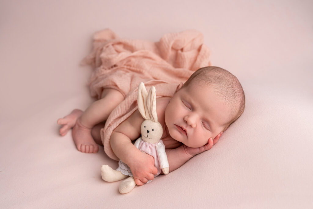 Newborn Photography 5 sleeping baby girl on pink with a little bunny in her hand